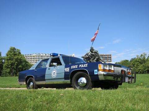 1991 Ford LTD Crown Victoria - Rear three-quarter view of a two-tone blue Massachusetts State Police cruiser marked 90E parked near the Iwo Jima Memorial.