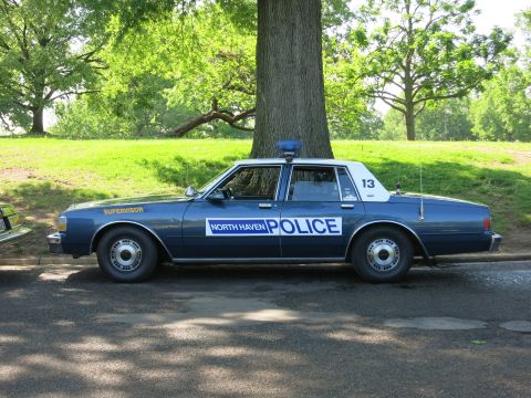 1991 Ford LTD Crown Victoria - dark blue North Haven Police Chevrolet Caprice cruiser marked 'Supervisor' and number 13 is parked beside a tree.