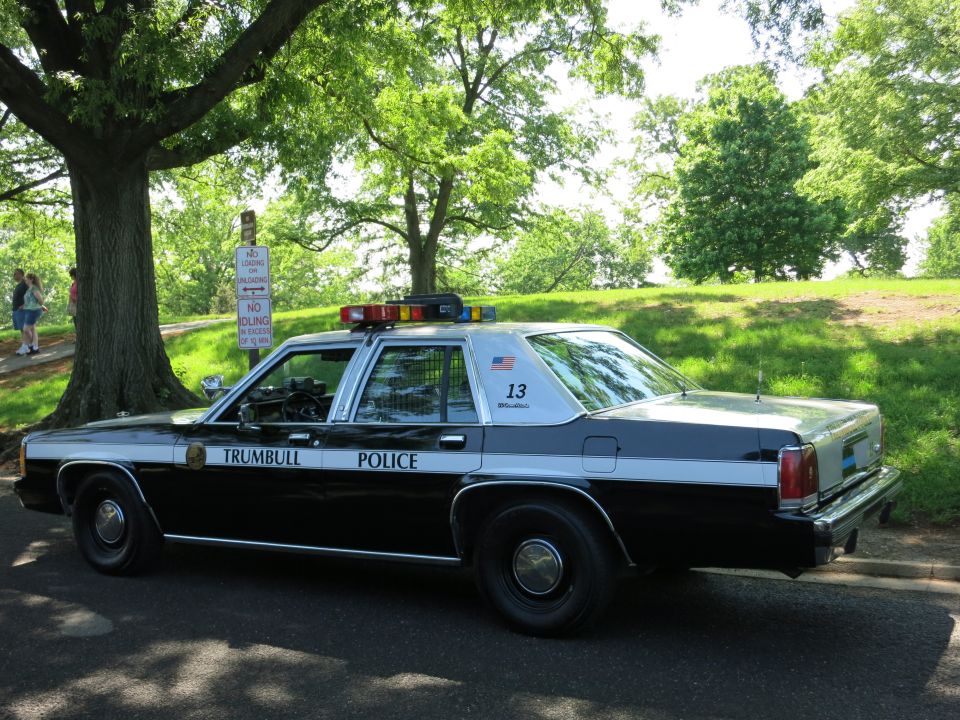 Rear three-quarter view of black and white Trumbull Police Ford sedan number 13