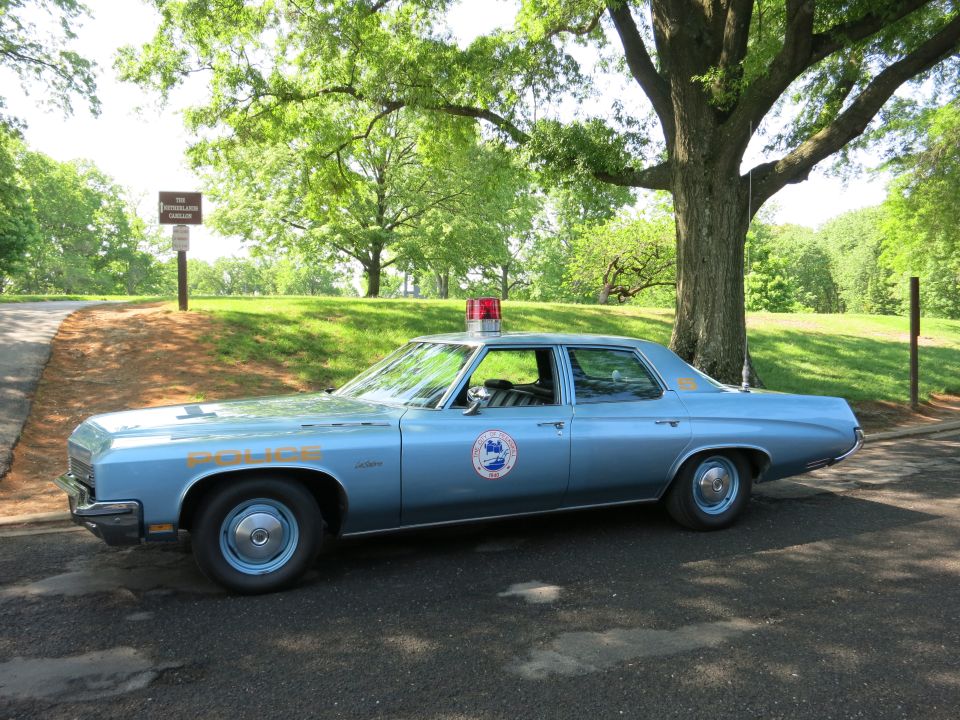 Light blue police Buick sedan with red dome light and door shield in profile