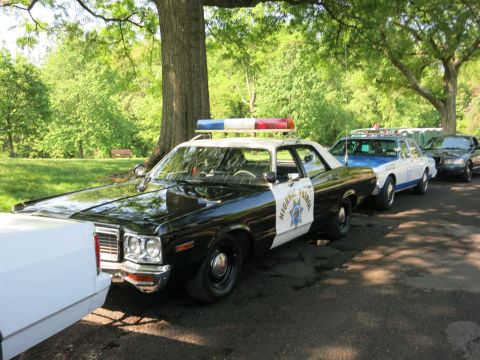 1991 Ford LTD Crown Victoria - black-and-white Highway Patrol sedan with red and blue dome lights parked ahead of a police station wagon in a park.