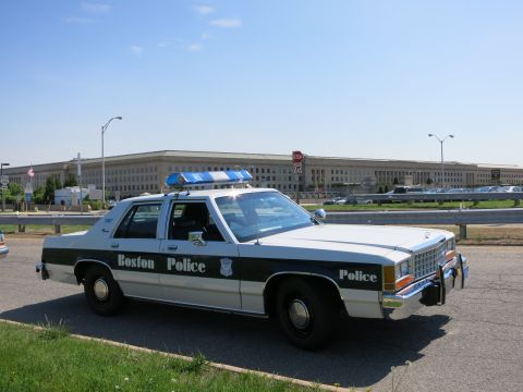 1991 Ford LTD Crown Victoria - black-and-white Boston Police Ford Crown Victoria cruiser parked in front of the Pentagon building under a clear sky.