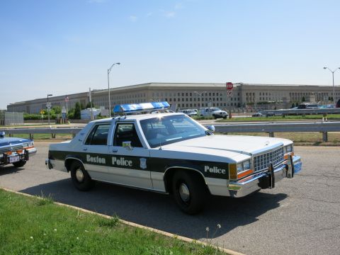 1991 Ford LTD Crown Victoria - white and blue 'Boston Police' Ford LTD Crown Victoria sedan with roof lightbar parked on grass in front of the Pentagon building.