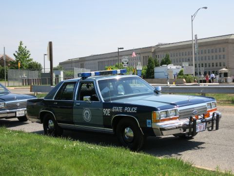 1991 Ford LTD Crown Victoria - black and gray Massachusetts State Police Ford sedan numbered 90E with push bar and roof lightbar parked in front of the Pentagon.