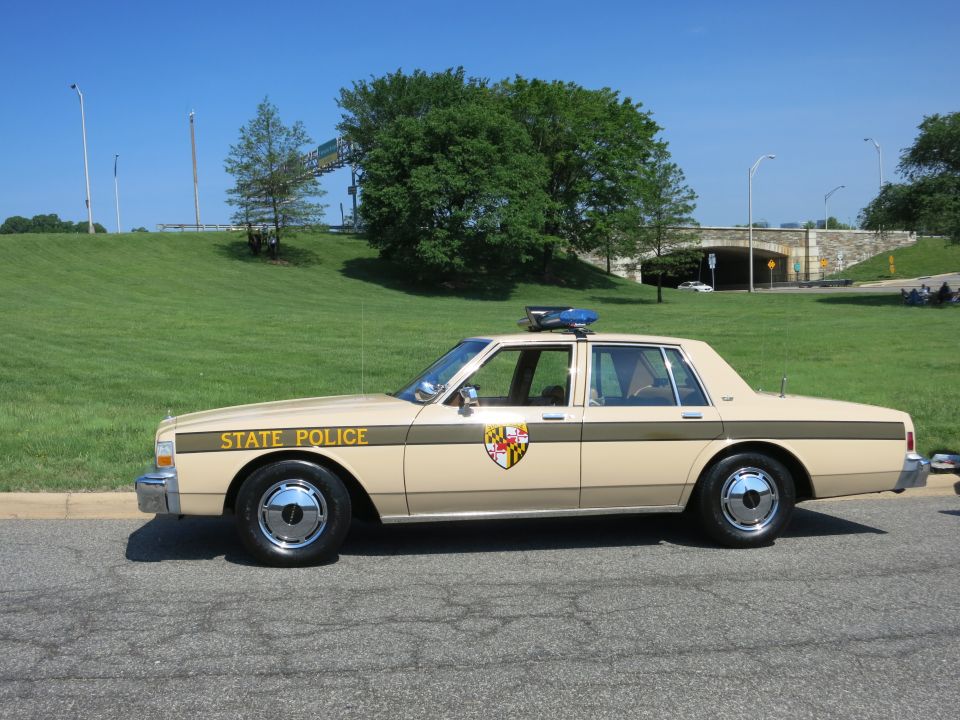 Tan and brown State Police Chevrolet sedan with shield emblem roadside