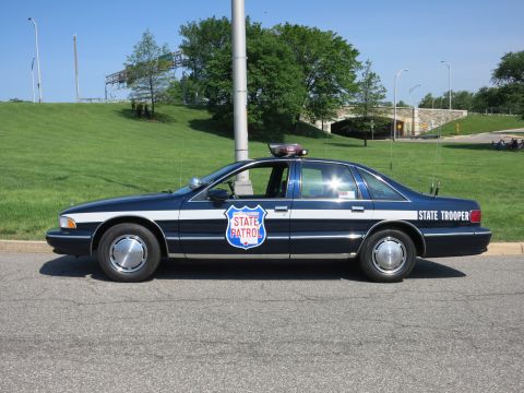 1991 Ford LTD Crown Victoria - Profile of a dark blue and white Chevrolet Caprice 'State Trooper' sedan with 'State Patrol' door shield parked on a road.