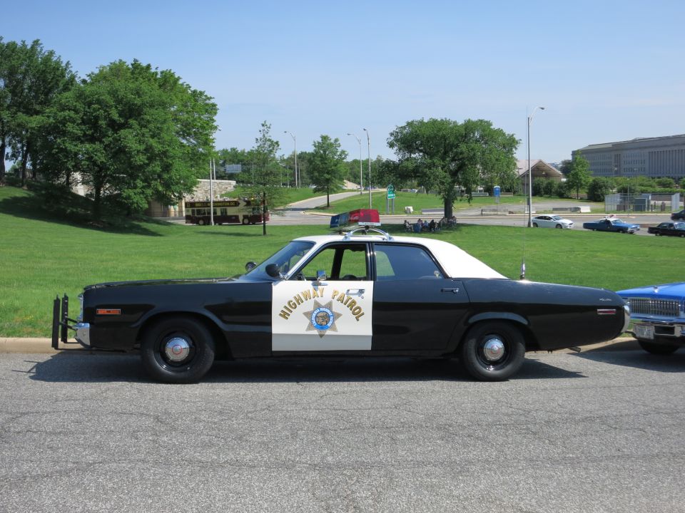 Black and white HIGHWAY PATROL sedan with white roof and star door shield, parked roadside