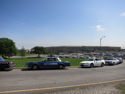 1991 Ford LTD Crown Victoria - blue North Haven Police sedan leads a row of police cars parked along a road in front of the Pentagon building.