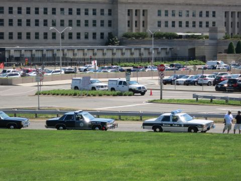1991 Ford LTD Crown Victoria - State Police cruiser and a Boston Police cruiser are parked on a grassy slope before a large stone government building.