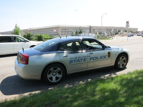 1991 Ford LTD Crown Victoria - silver 'Virginia State Police' Dodge Charger parked roadside, viewed from the rear, with the Pentagon and an aircraft overhead.