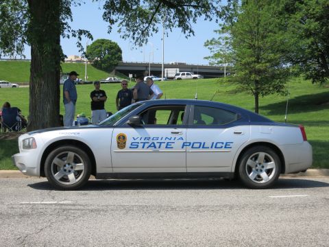 1991 Ford LTD Crown Victoria - silver 'Virginia State Police' Dodge Charger shown in profile, parked by a grassy area with onlookers and an overpass.