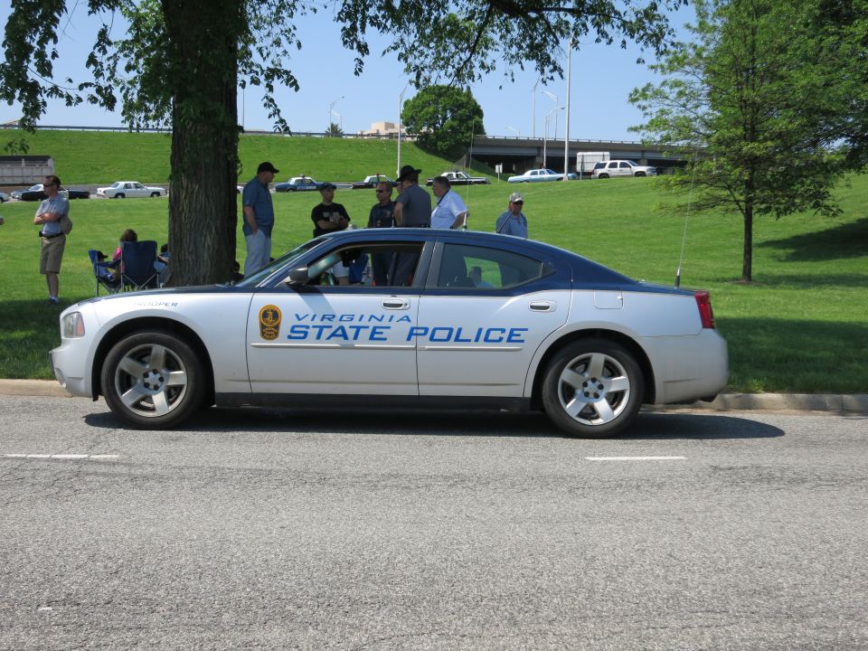 Silver Virginia State Police Dodge Charger, side view, group of people behind
