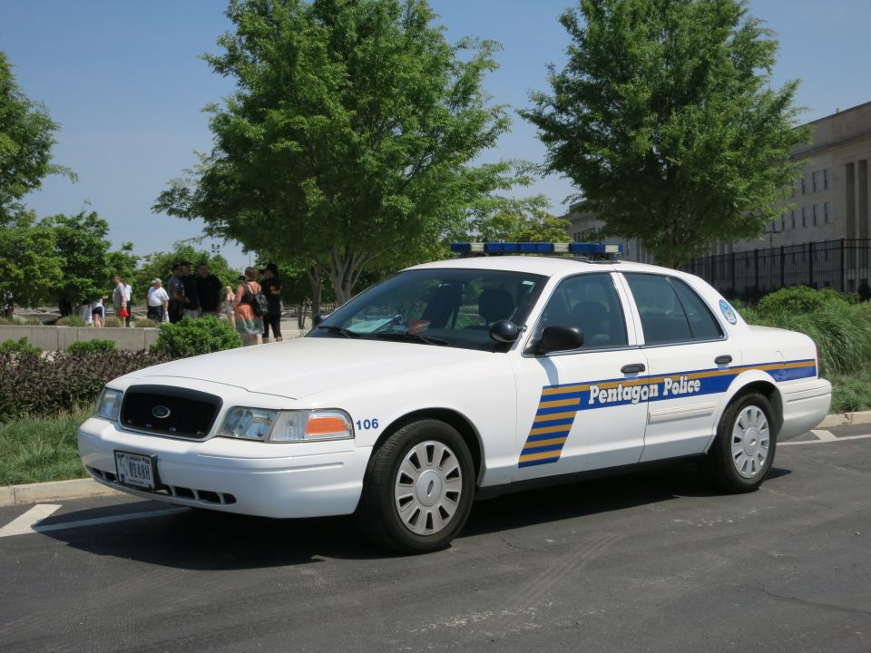 White Ford Crown Victoria marked Pentagon Police unit 106 parked near building