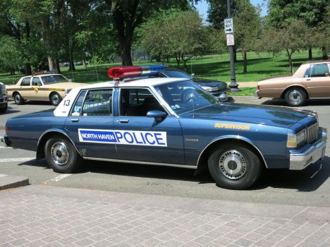 1991 Ford LTD Crown Victoria - blue North Haven Police Supervisor sedan with a red roof lightbar parked on pavers, other patrol cars behind it.