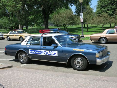 1991 Ford LTD Crown Victoria - blue North Haven Police Supervisor sedan, unit 13, with a red and blue lightbar parked at a curb among other cruisers.