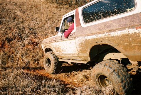 1978 Ford Bronco - 1978 Ford Bronco navigating rough terrain, coated in mud.