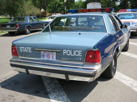 1991 Ford LTD Crown Victoria - Rear view of a light blue Ford State Police sedan with a Massachusetts plate reading 90 E, parked among other cruisers.