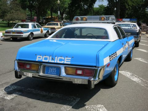 1991 Ford LTD Crown Victoria - Rear quarter view of a blue police sedan lettered Police, unit 2655, with a NYC Police plate parked among vintage cruisers.