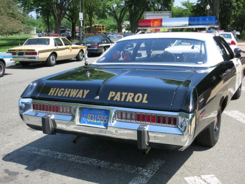 1991 Ford LTD Crown Victoria - Rear view of a black police sedan lettered Highway Patrol with a roof lightbar parked among other vintage patrol cars.