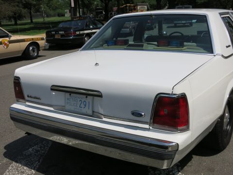 1991 Ford LTD Crown Victoria - Rear view of a white two-door coupe with a Metro Police official plate reading 291, parked among other cruisers.