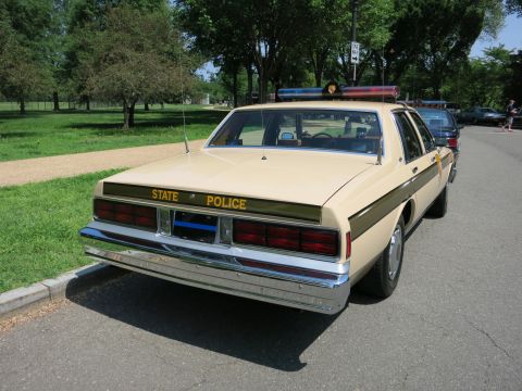 1991 Ford LTD Crown Victoria - Rear view of a tan four-door sedan lettered STATE POLICE with a roof light bar, parked beside a grassy field.