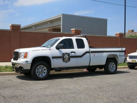 1991 Ford LTD Crown Victoria - white GMC extended-cab pickup with Newark Police emergency-services markings parked by a brick wall.