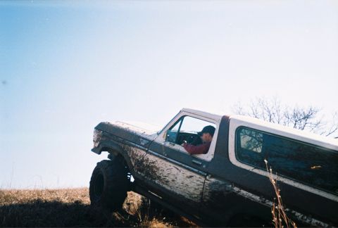 1978 Ford Bronco - A 1978 Ford Bronco navigates an off-road trail, its body covered in mud from the climb.