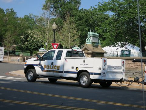 1991 Ford LTD Crown Victoria - white Ford Super Duty utility-bed pickup lettered POLICE United States Capitol parked on a curved street near a monument.