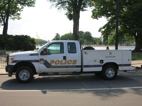 1991 Ford LTD Crown Victoria - Side view of a white Ford Super Duty utility pickup lettered POLICE United States Capitol parked beside a metal fence.