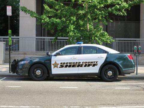 1991 Ford LTD Crown Victoria - Side view of a green-and-white Broward County Sheriff Ford Taurus police sedan parked at a downtown curb.