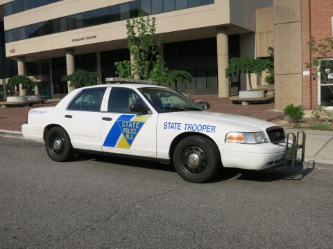1991 Ford LTD Crown Victoria - white Ford Crown Victoria marked New Jersey State Police 'State Trooper' is parked along a curb in front of an office building.