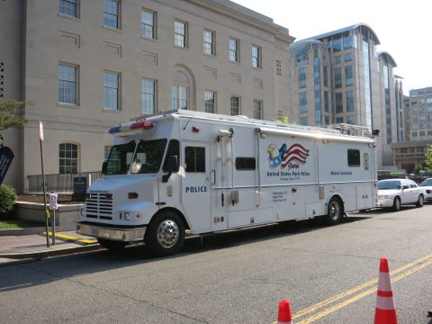 1991 Ford LTD Crown Victoria - large white United States Park Police Mobile Command truck is parked along a street in front of a stone government building.
