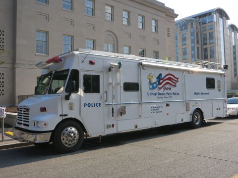 1991 Ford LTD Crown Victoria - Side view of a white United States Park Police Mobile Command truck parked at the curb of a stone building.
