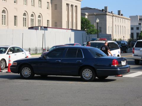 1991 Ford LTD Crown Victoria - dark blue Ford Crown Victoria sedan is parked at an intersection with marked police vehicles and officers in the background.