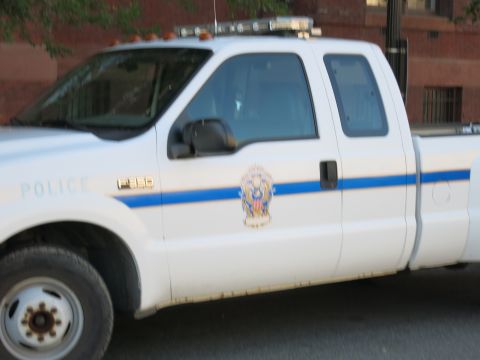 1991 Ford LTD Crown Victoria - Close-up side view of a white Ford F-350 Police pickup truck with a roof light bar and a badge emblem on the door.