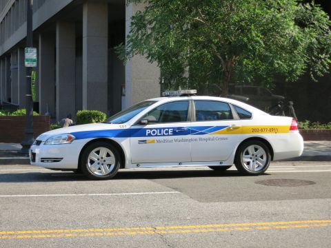 1991 Ford LTD Crown Victoria - white Chevrolet Impala marked Police / MedStar Washington Hospital Center with blue and yellow graphics is parked on a street.
