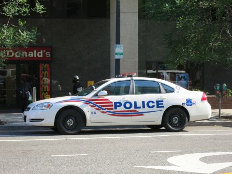 1991 Ford LTD Crown Victoria - white Chevrolet Impala marked Police with red and blue graphics is parked on a street in front of a McDonald's restaurant.
