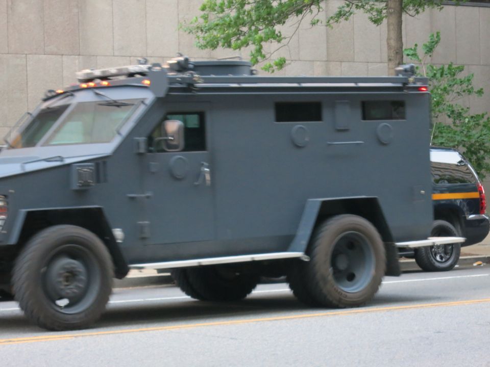 Side view of a dark gray armored police tactical truck on a street