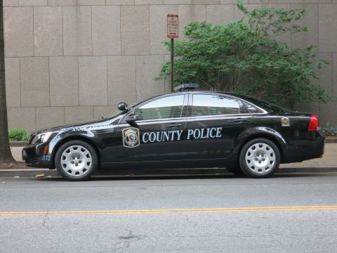1991 Ford LTD Crown Victoria - black County Police sedan with white lettering and unit number 372 parked along an urban curb.