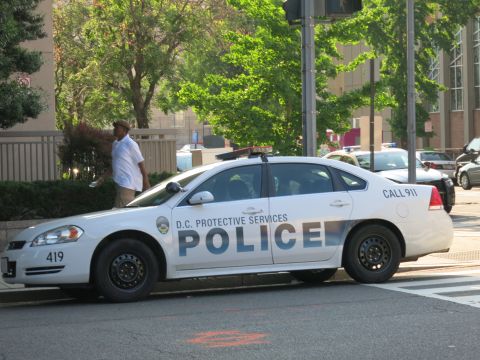 1991 Ford LTD Crown Victoria - white D.C. Protective Services police sedan unit 419 stopped at an intersection with a pedestrian nearby.