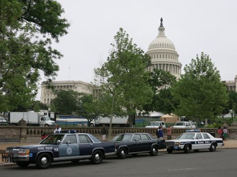 1991 Ford LTD Crown Victoria - navy State Police sedan, a dark unmarked sedan, and a Boston Police cruiser line a street with the U.S. Capitol dome behind.