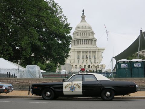 1991 Ford LTD Crown Victoria - black and white Highway Patrol sedan with red roof light parked in front of the U.S. Capitol dome and white tents.