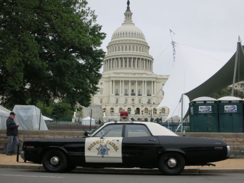 1991 Ford LTD Crown Victoria - black and white Highway Patrol car parked at a curb with the U.S. Capitol dome behind and a person standing nearby.