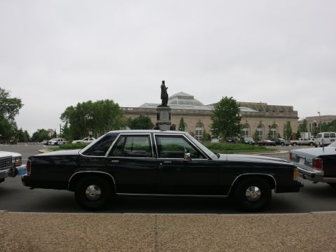1991 Ford LTD Crown Victoria - black Ford full-size four-door sedan parked in a lot in front of a large domed stone building with a statue.