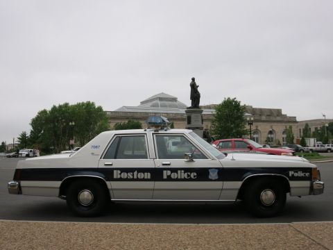 1991 Ford LTD Crown Victoria - white-and-blue Ford full-size sedan lettered Boston Police parked in front of a domed stone building with a statue.