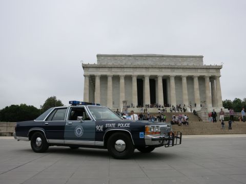 1991 Ford LTD Crown Victoria - navy and silver "90E State Police" Ford cruiser with push bar, viewed from the front three-quarter angle before the Lincoln Memorial.
