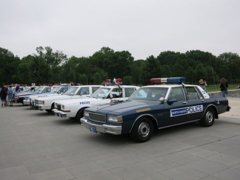 1991 Ford LTD Crown Victoria - row of vintage police sedans parked at an angle, the nearest a navy "North Haven Police" Chevrolet, with white "Police" cars behind it.