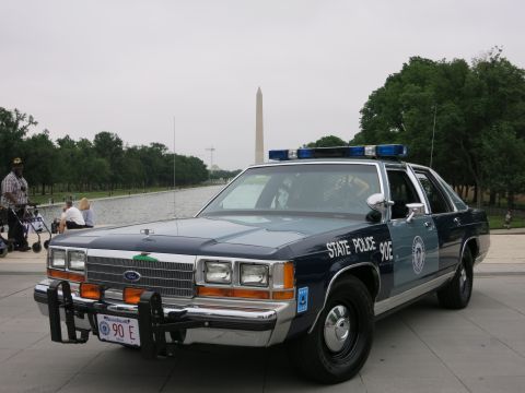 1991 Ford LTD Crown Victoria - navy and silver "State Police 90E" Ford cruiser sits beside the Reflecting Pool with the Washington Monument rising in the distance.