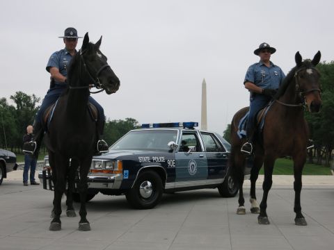 1991 Ford LTD Crown Victoria - Two officers in campaign hats sit on dark and bay horses in front of a navy "State Police 90E" Ford cruiser with the Washington Monument be…