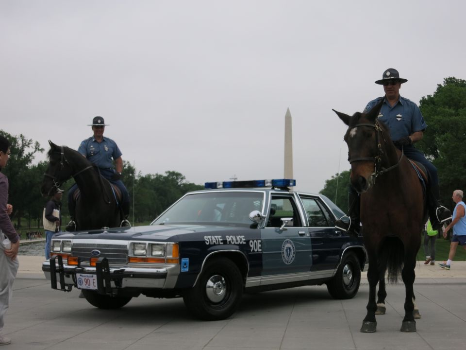 Two mounted officers and a State Police cruiser with the Washington Monument